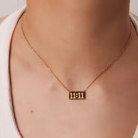 Gold 11:11 pendant worn on model in a white tank top