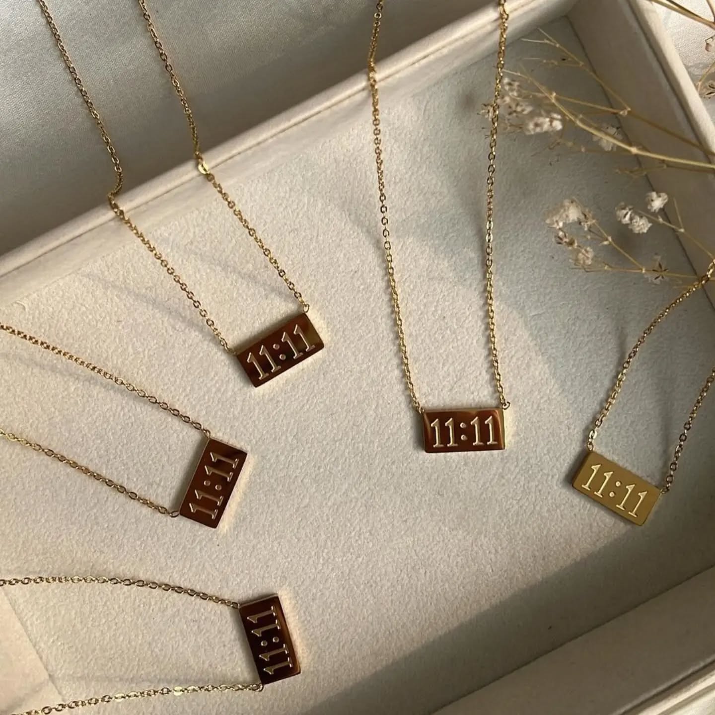 Multiple 11:11 pendant necklaces displayed in a cream jewelry box