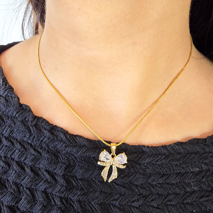 Model wearing AD Bow Necklace – delicate gold chain with crystal bow pendant.