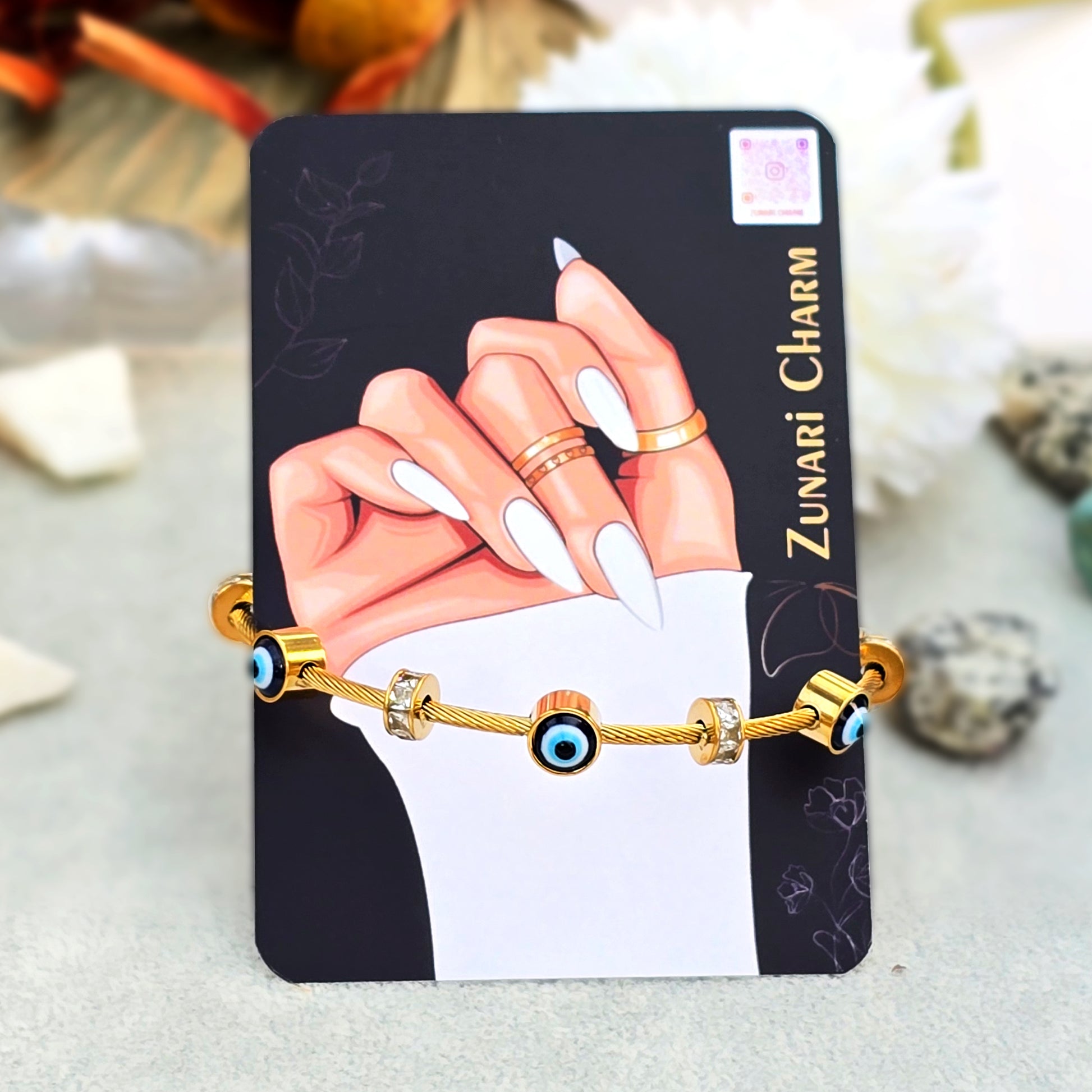 Amulet evil eye bangle displayed on Zunari Charm branded packaging card with manicure art.