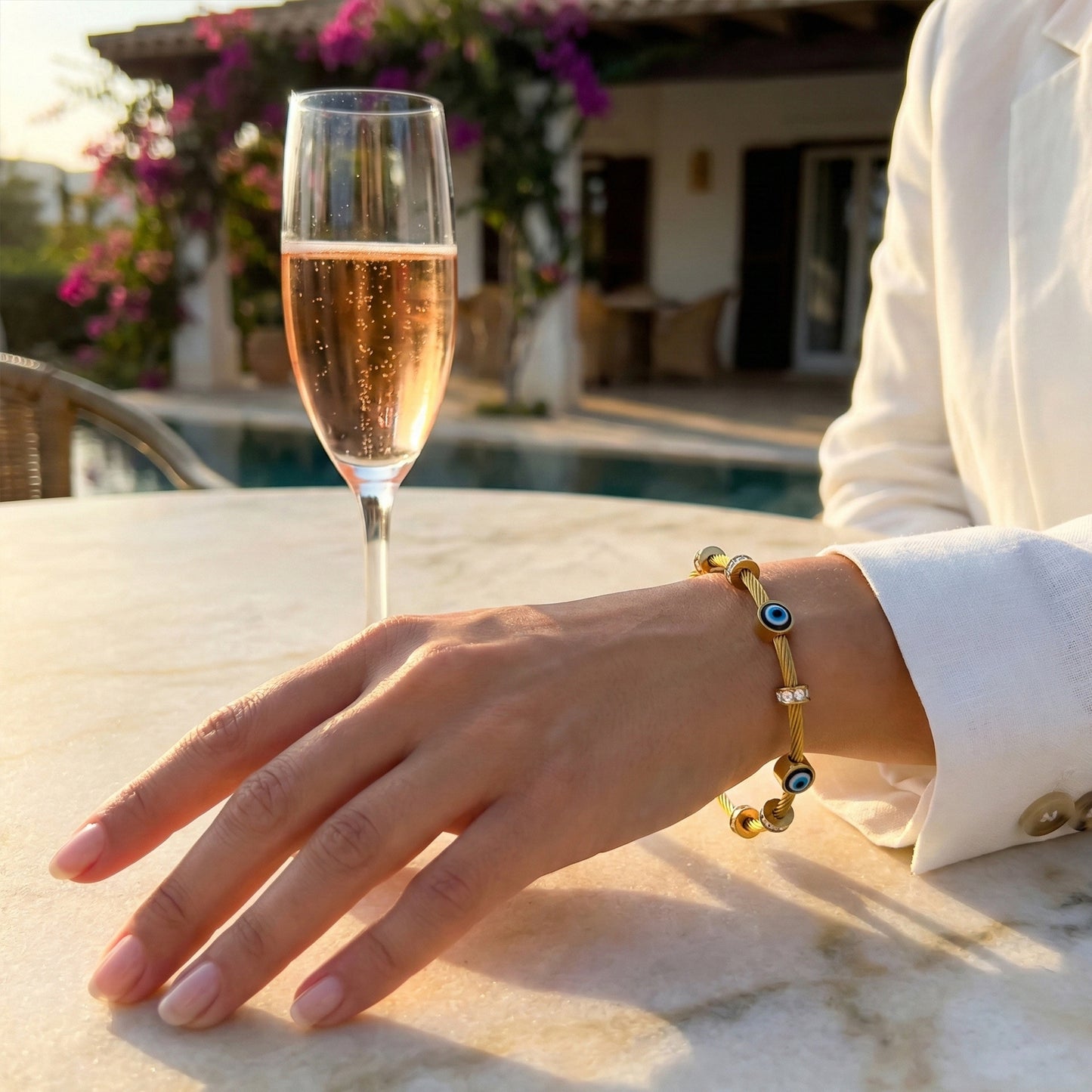 Woman wearing gold Amulet cable bangle styled with a white blazer for a luxury resort look.