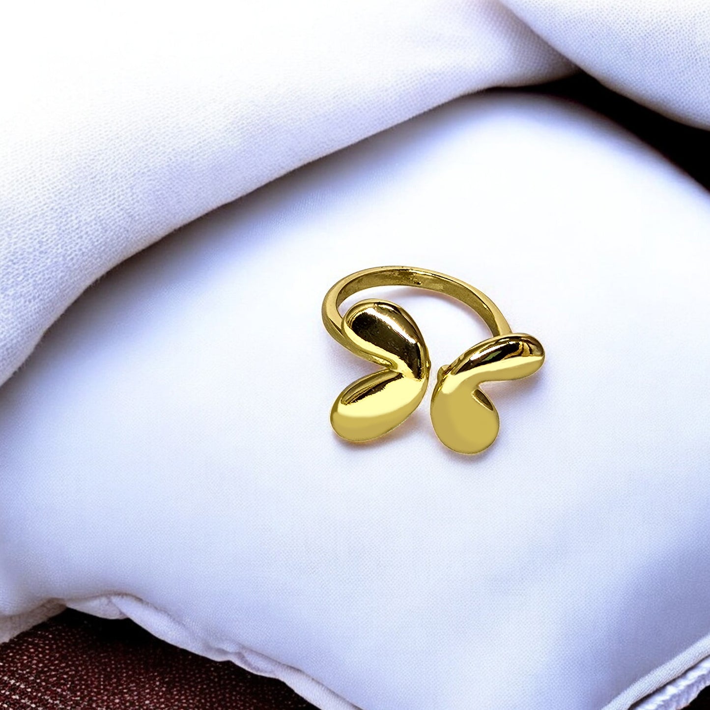 Angel Wings Ring – shiny gold statement ring placed on soft white cushion