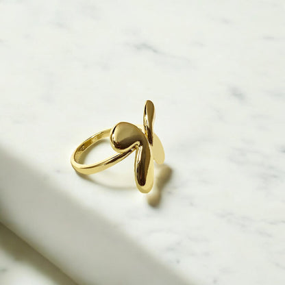 Angel Wings Ring – gold-toned adjustable open ring with twin wing motifs on marble background