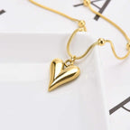 Close-up of shiny teardrop heart pendant on plate with part of chain visible