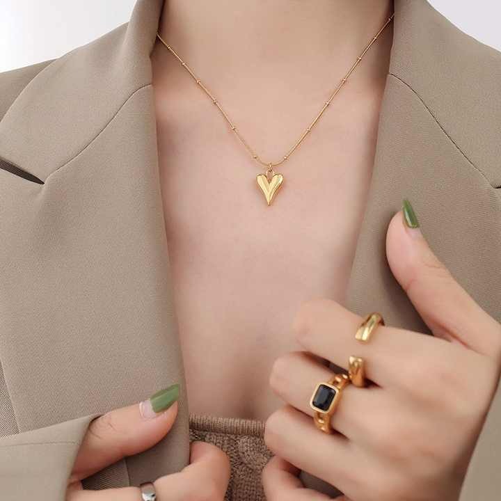 Necklace worn by model with blazer and stacked gold rings