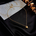 Necklace styled on black silk background beside golden décor and invitation card