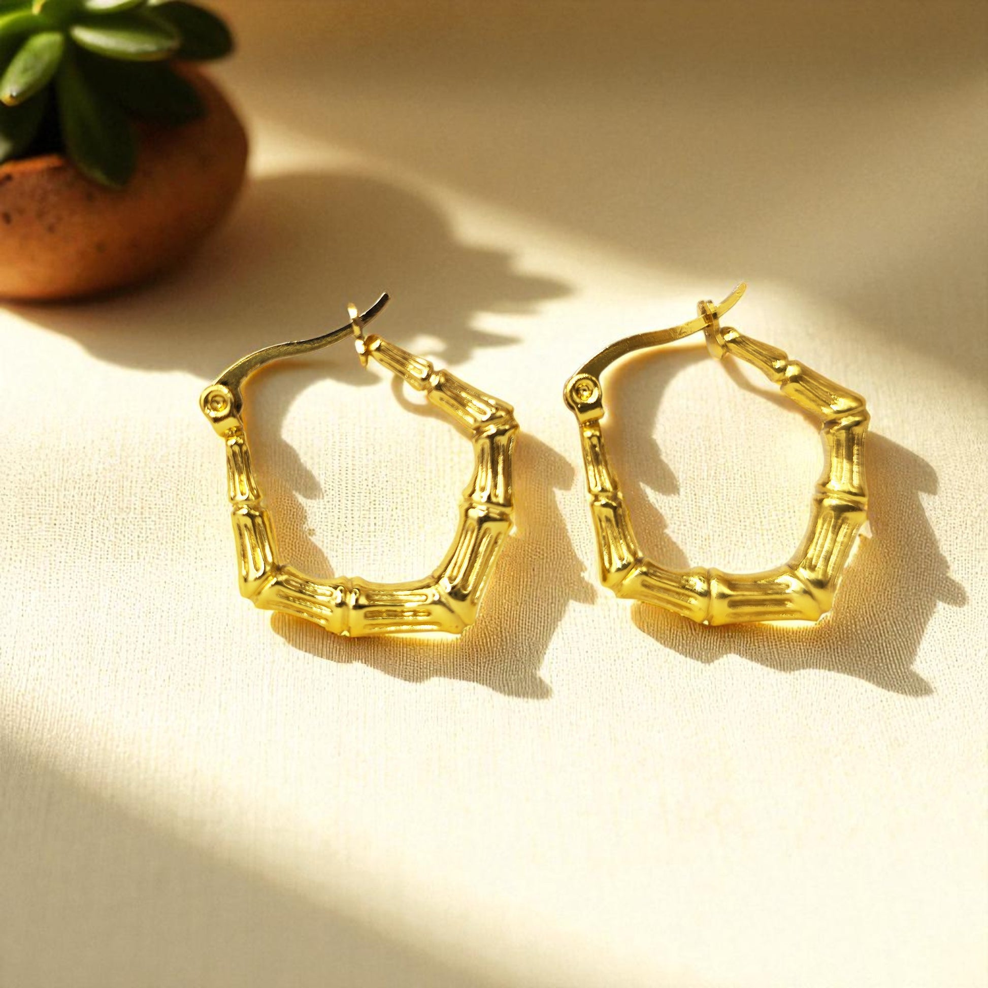 Bamboo Luxe Earrings – gold textured hoops in natural light on beige fabric