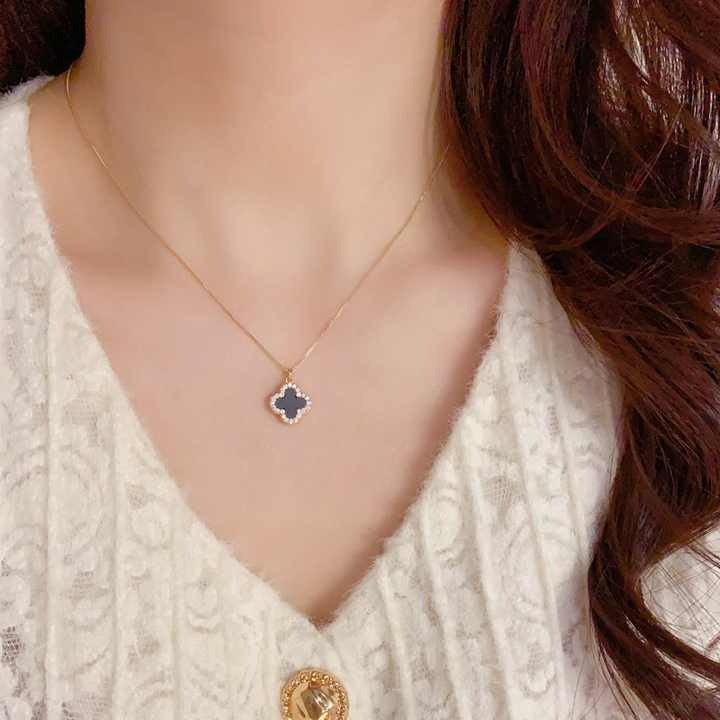Model wearing black clover necklace with off-white knit top