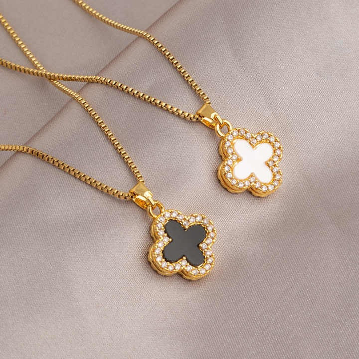 Side-by-side gold clover necklaces in white and black