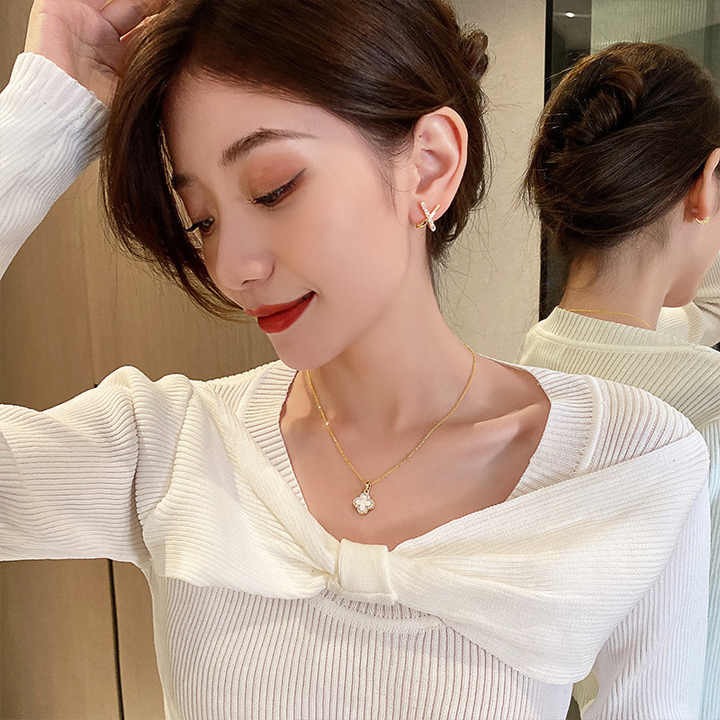 Model wearing white clover pendant necklace with white top
