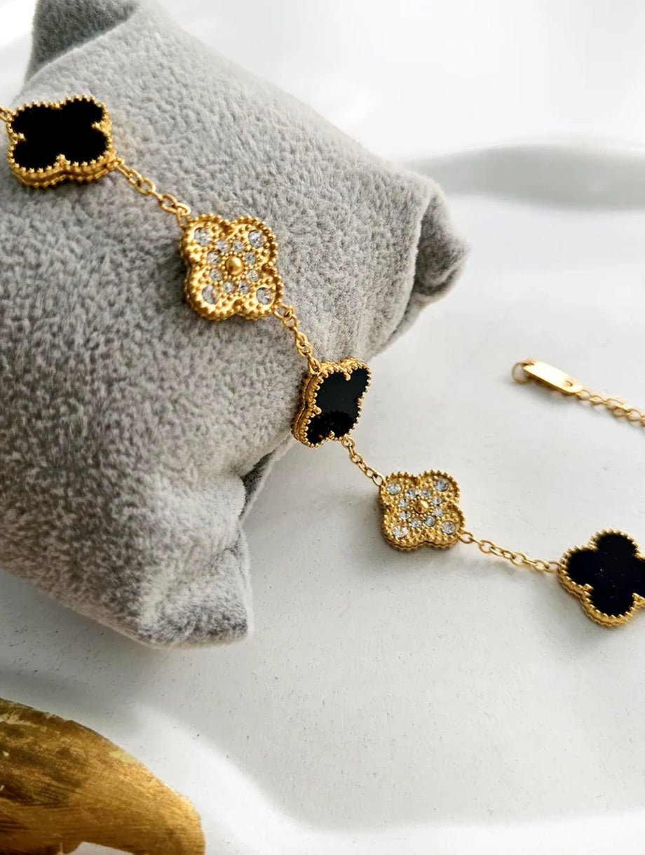Zunari Charm gold bracelet with black and crystal clovers on soft grey cushion