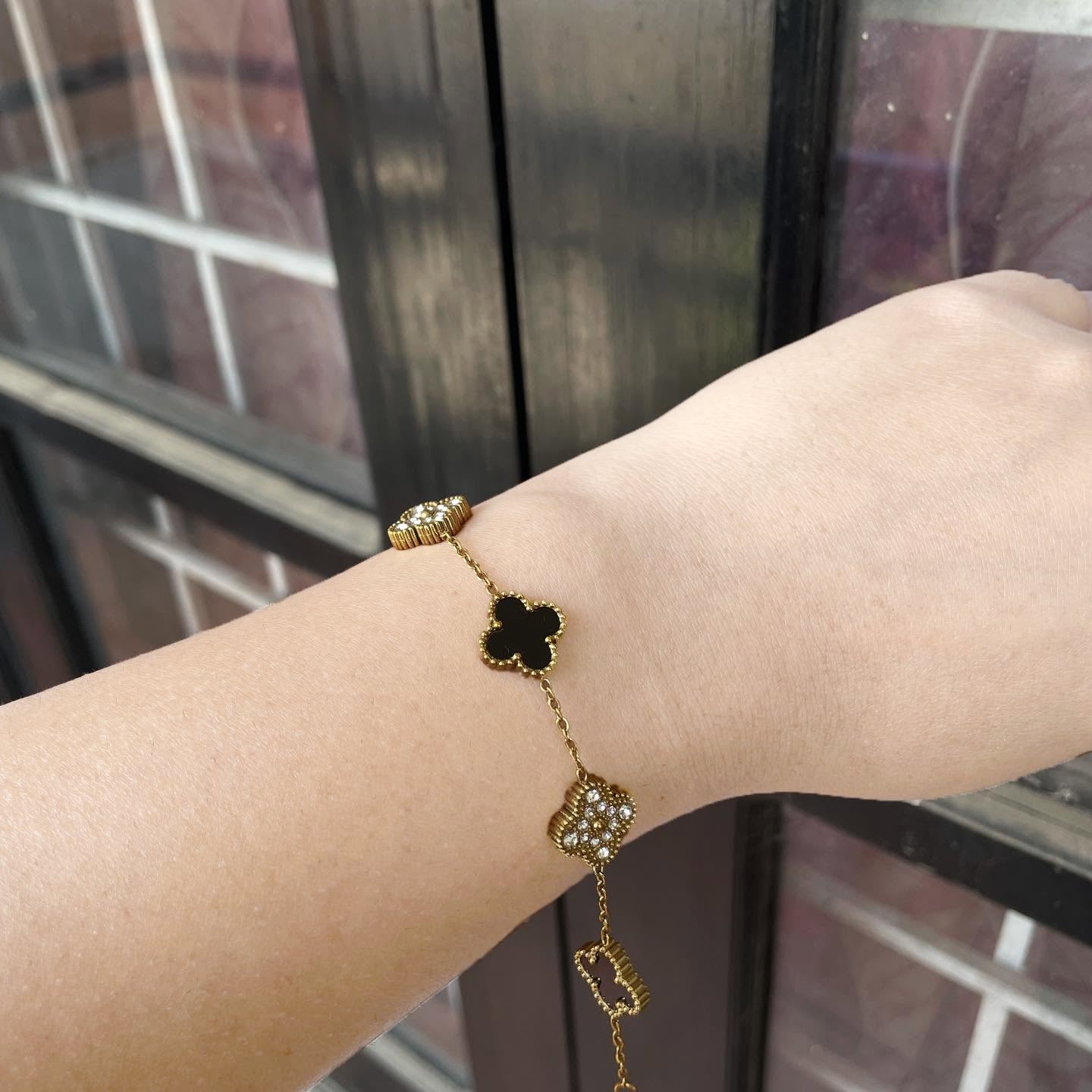 Gold clover charm bracelet worn on wrist outdoors