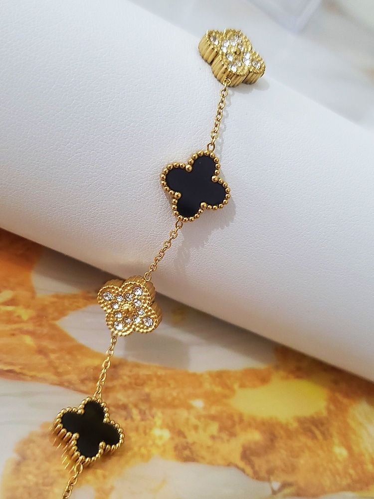 Close-up of black clover and zircon detail on gold bracelet