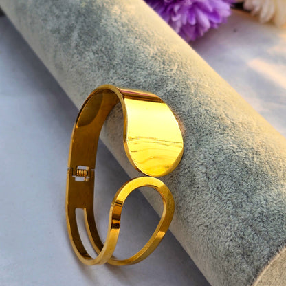 Sculptural gold bangle featuring a wide solid disc connecting to an open loop design.
