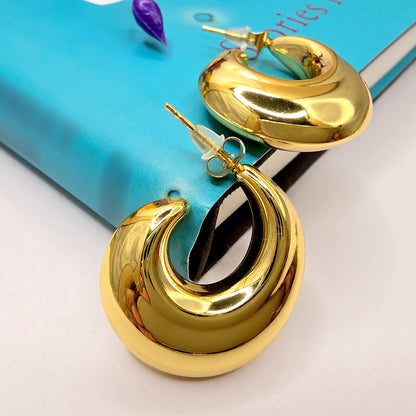 Sculptural gold loop earrings resting on a book cover