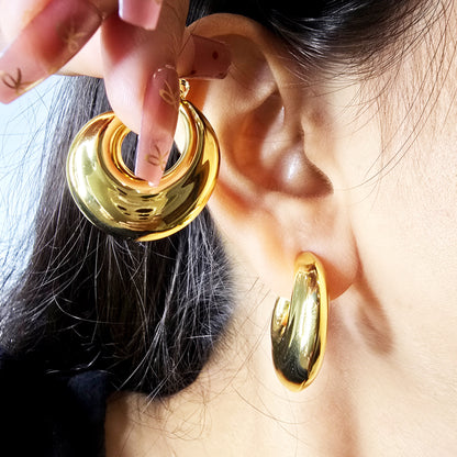Model wearing Bold Loop Earrings, showcasing bold sculptural hoop design