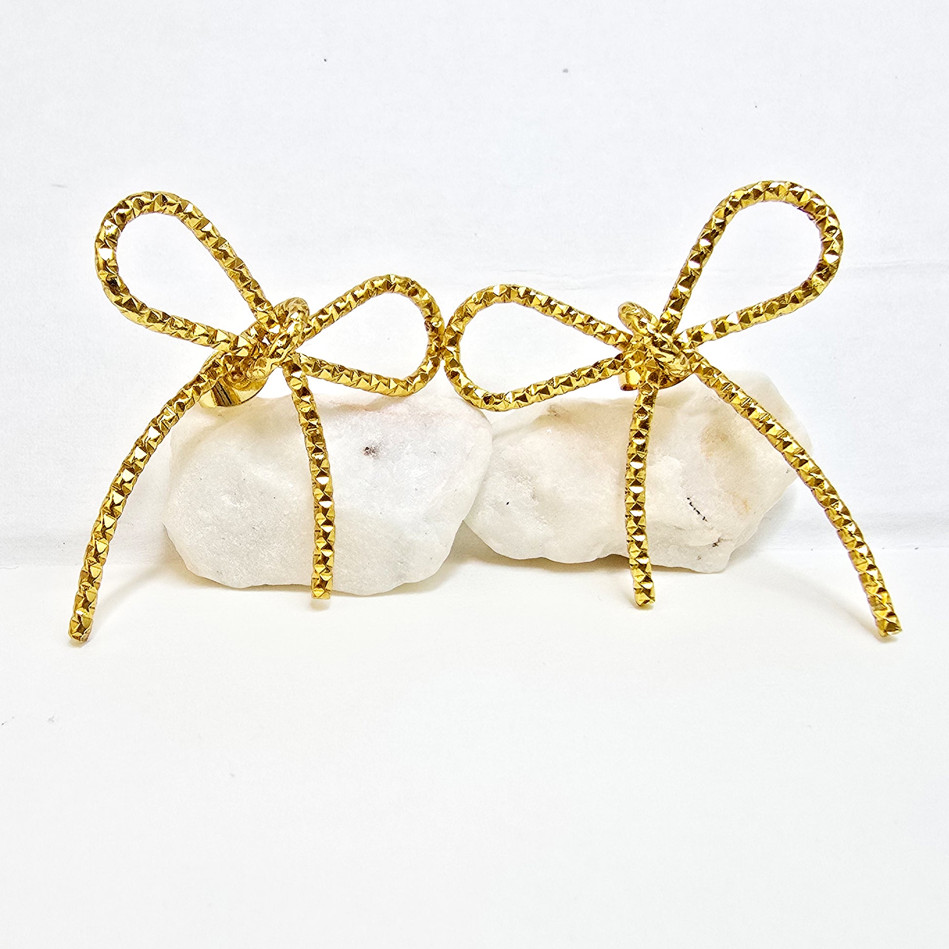 Close-up detail of textured surface on artificial gold bow knot stud earrings.
