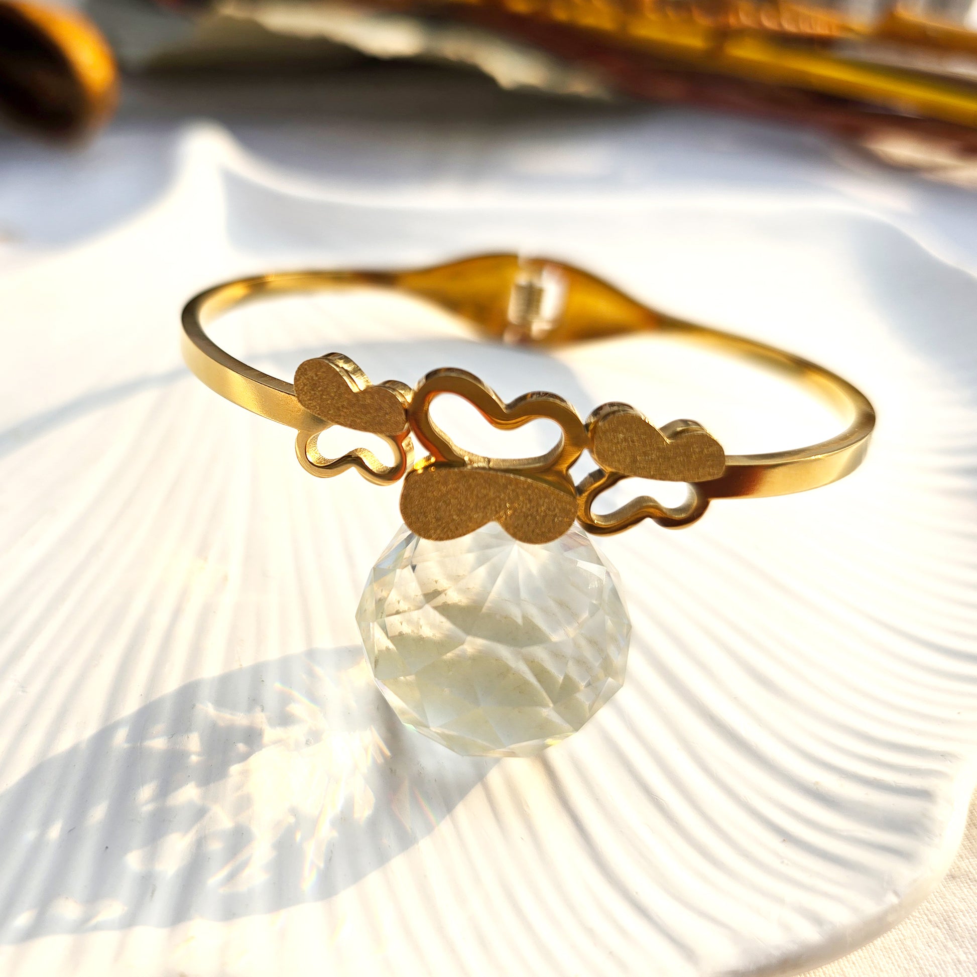Front view of gold bangle with three stardust texture butterflies on white shell.