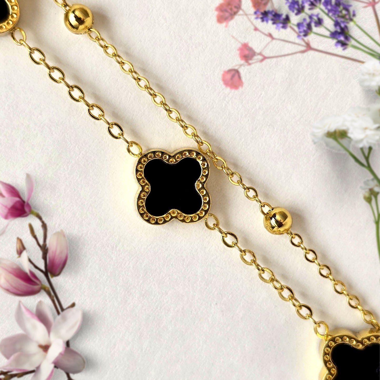 Close-up of black clover charm on gold layered bracelet with bead accents minimal anti tarnish jewelry