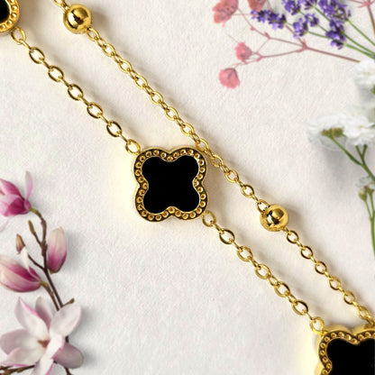 Close-up of black clover charm on gold layered bracelet with bead accents minimal anti tarnish jewelry