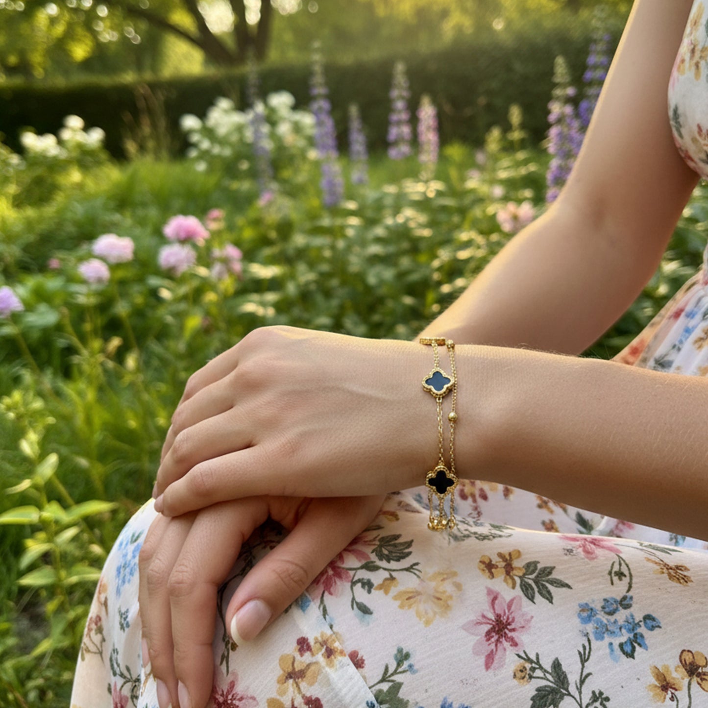 Woman wearing black clover layered gold bracelet outdoors styled with floral dress everyday luxury jewelry