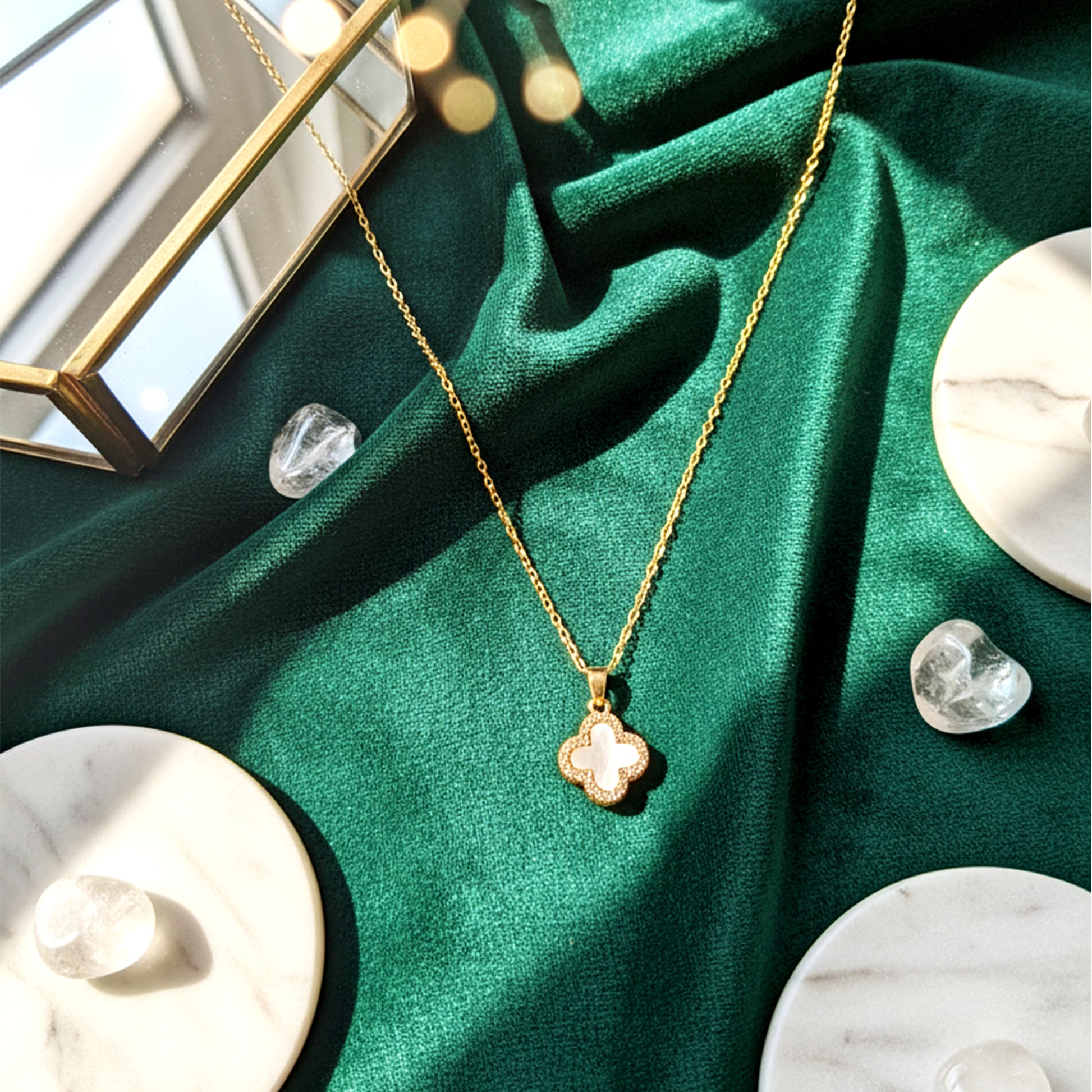 Crystal-paved side of the reversible four-leaf clover necklace styled on a green marble background.