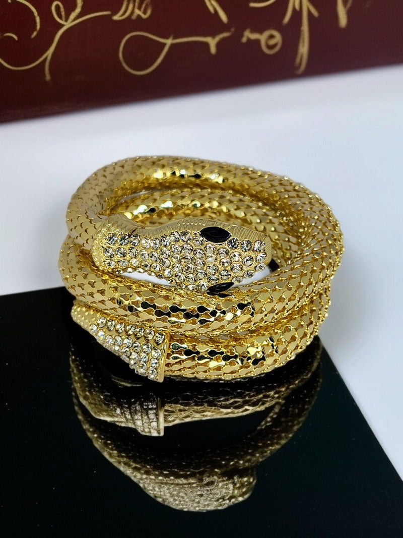 High-gloss serpent bracelet reflected on black mirror with red background