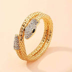 Close-up of gold snake cuff bracelet with shimmering scales on peach background