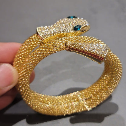 Hand-holding crystal-studded snake bracelet with teal eyes, side angle