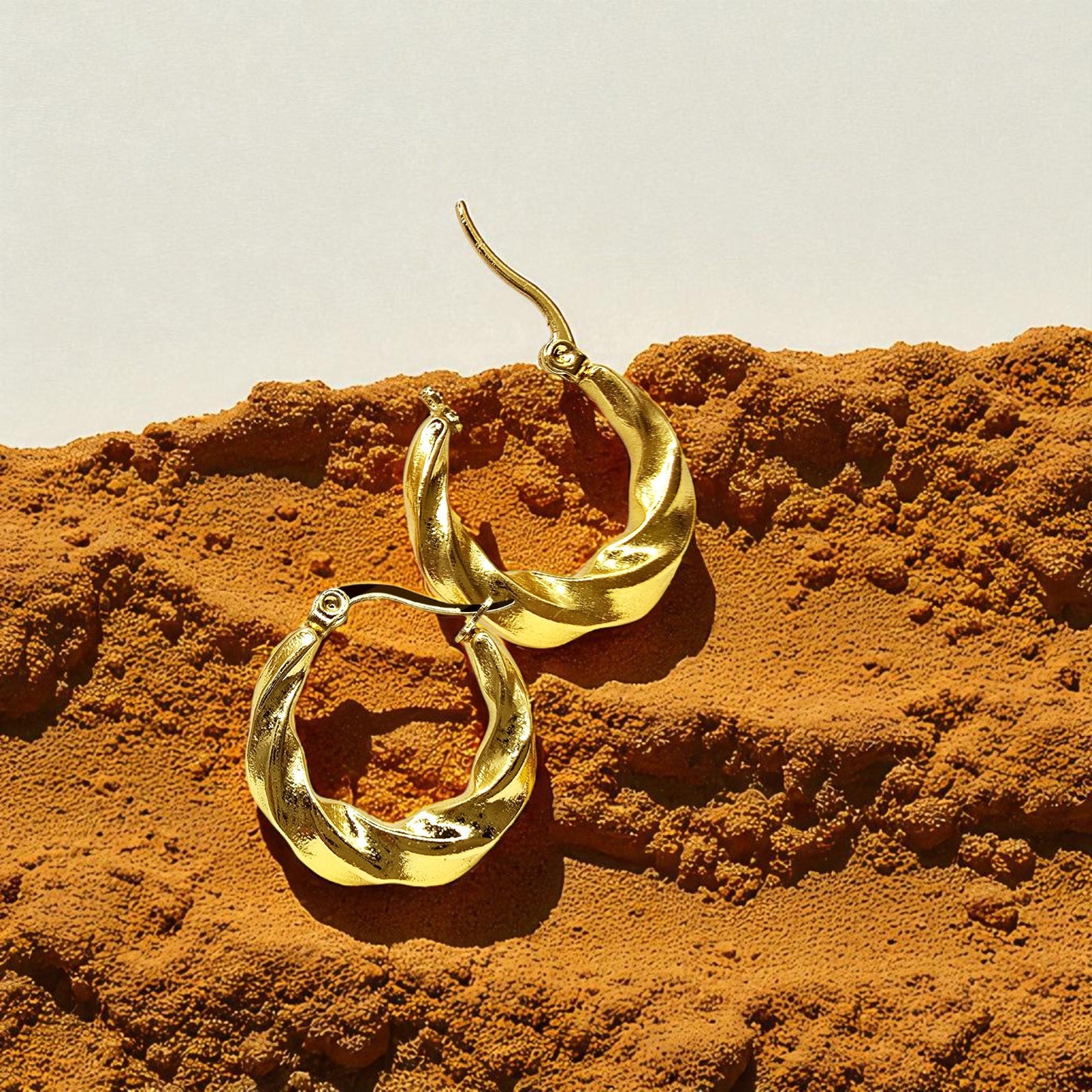 Curly Twist Earrings placed on earthy background with shadows