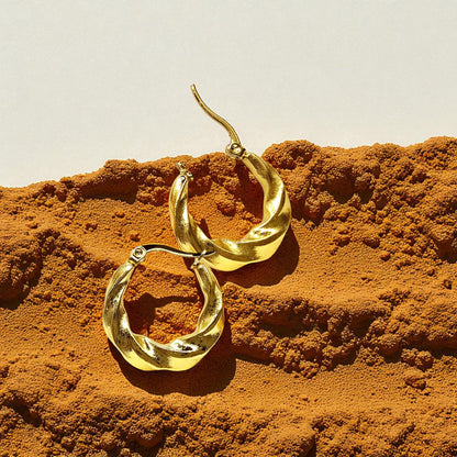 Curly Twist Earrings placed on earthy background with shadows