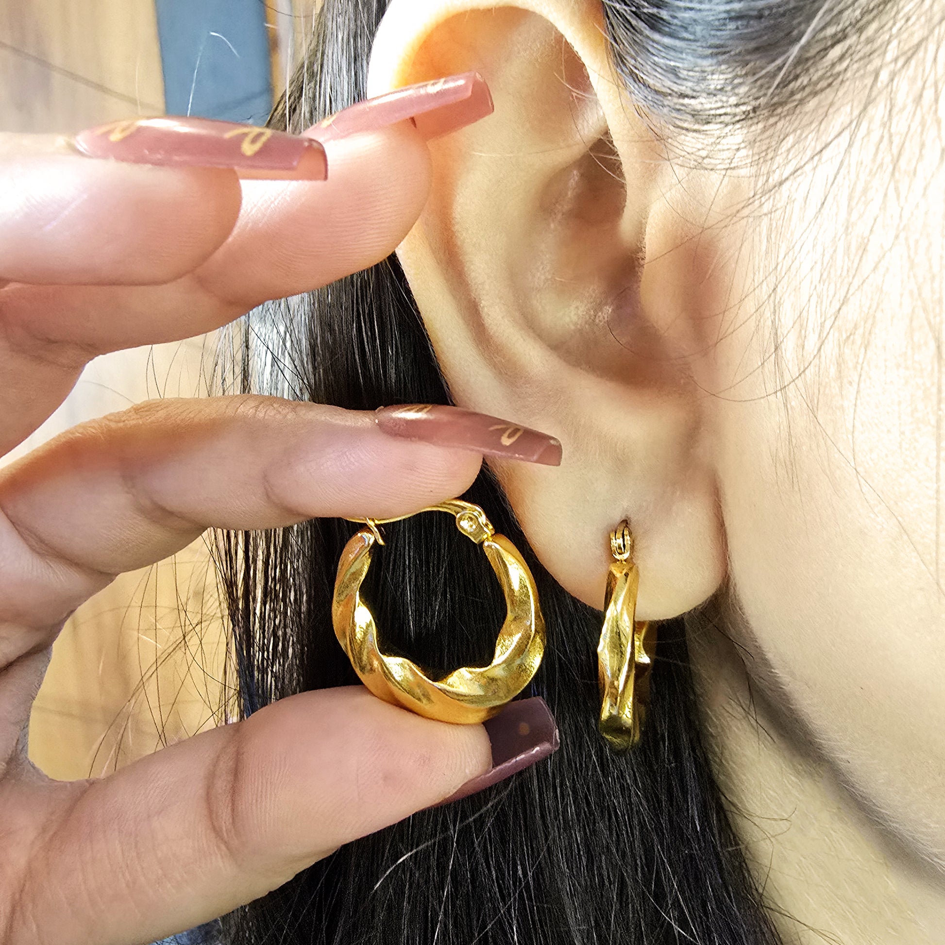 Model wearing Curly Twist Earrings—gold textured hoops close-up