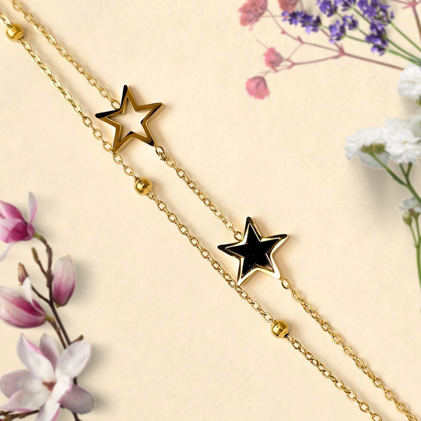 minimal gold bracelet with black and hollow star charms
