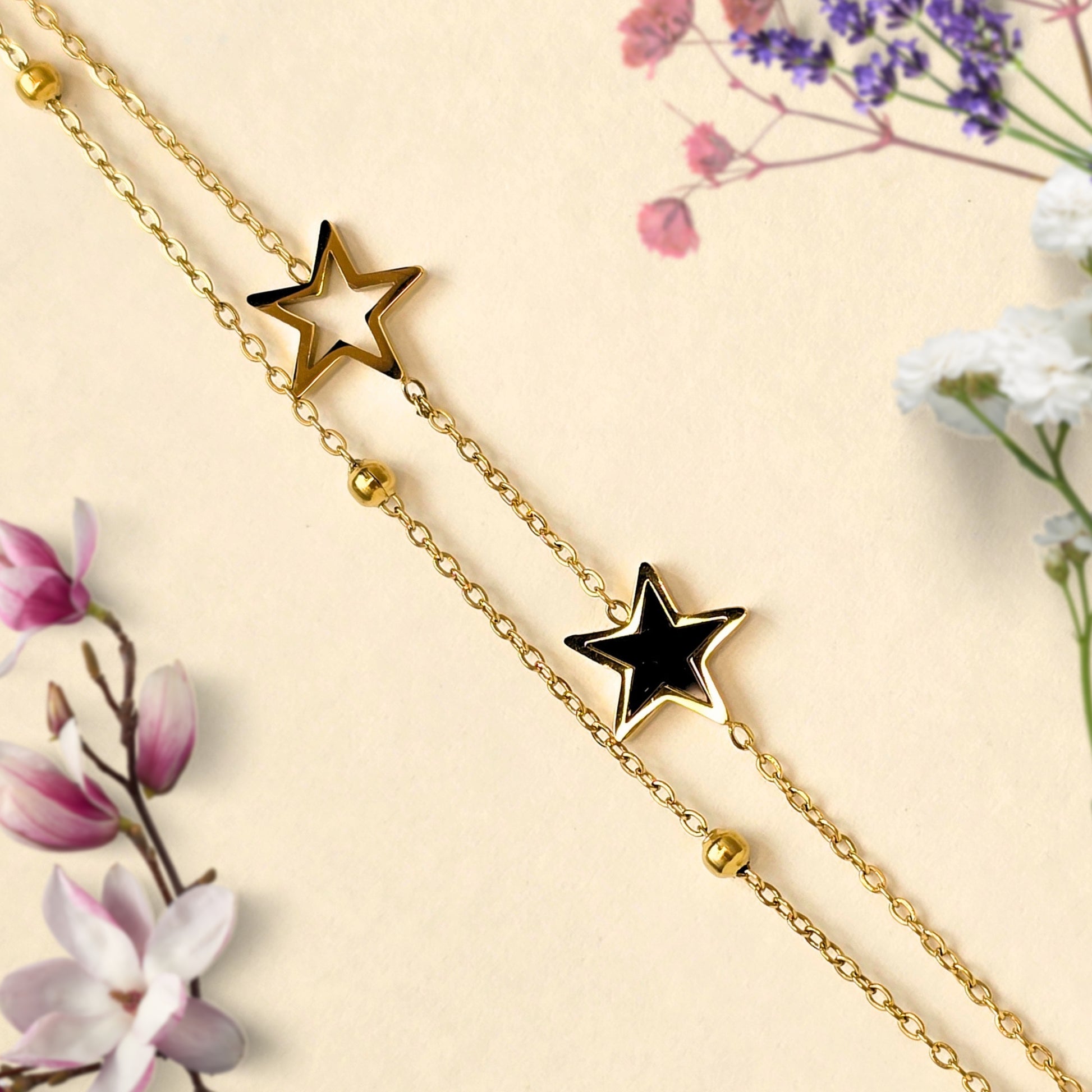 minimal gold bracelet with black and hollow star charms