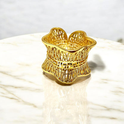 Studio shot of Empress Mesh Ring on a marble surface, showcasing elegant gold shine.