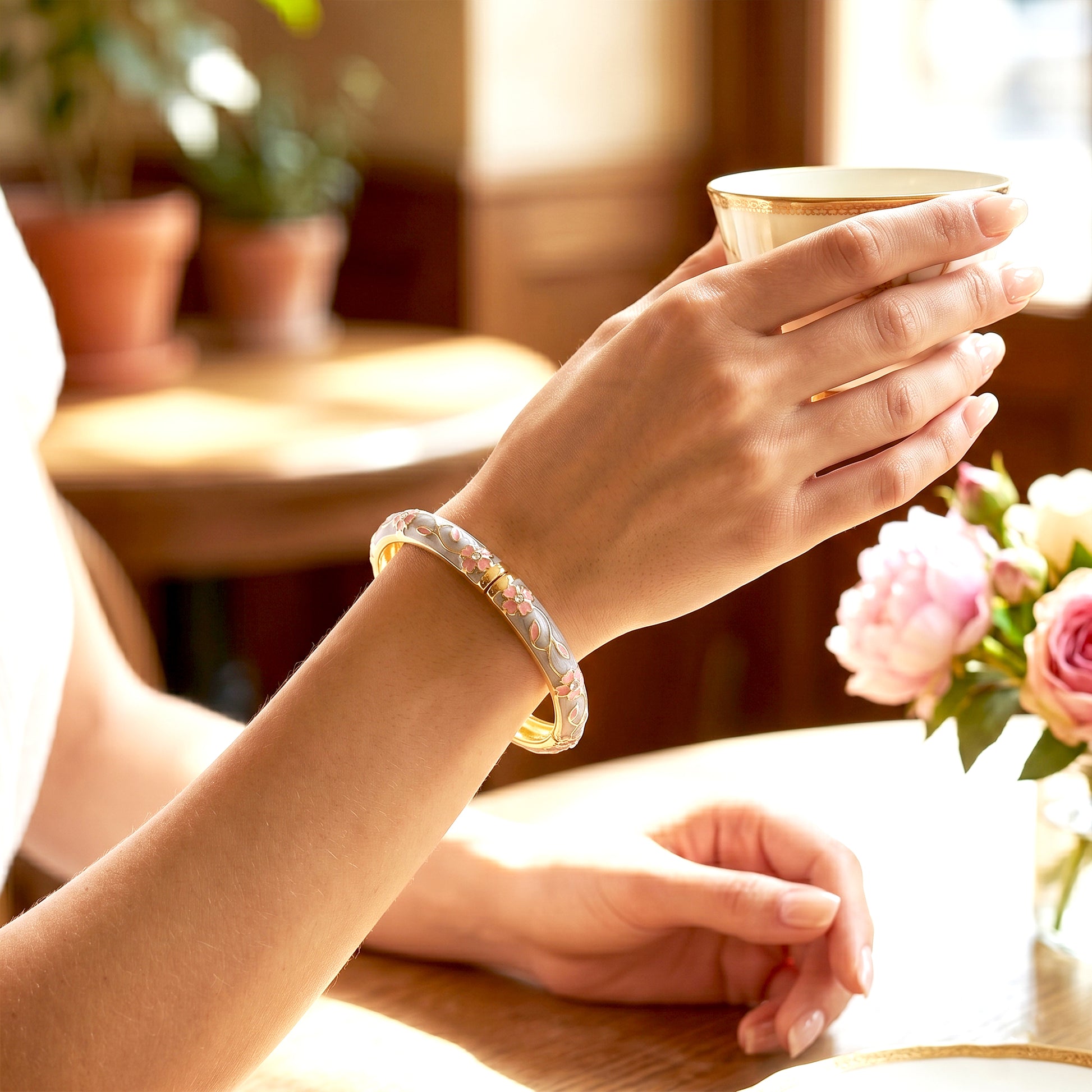 Grey enamel floral crystal bangle worn while holding tea cup