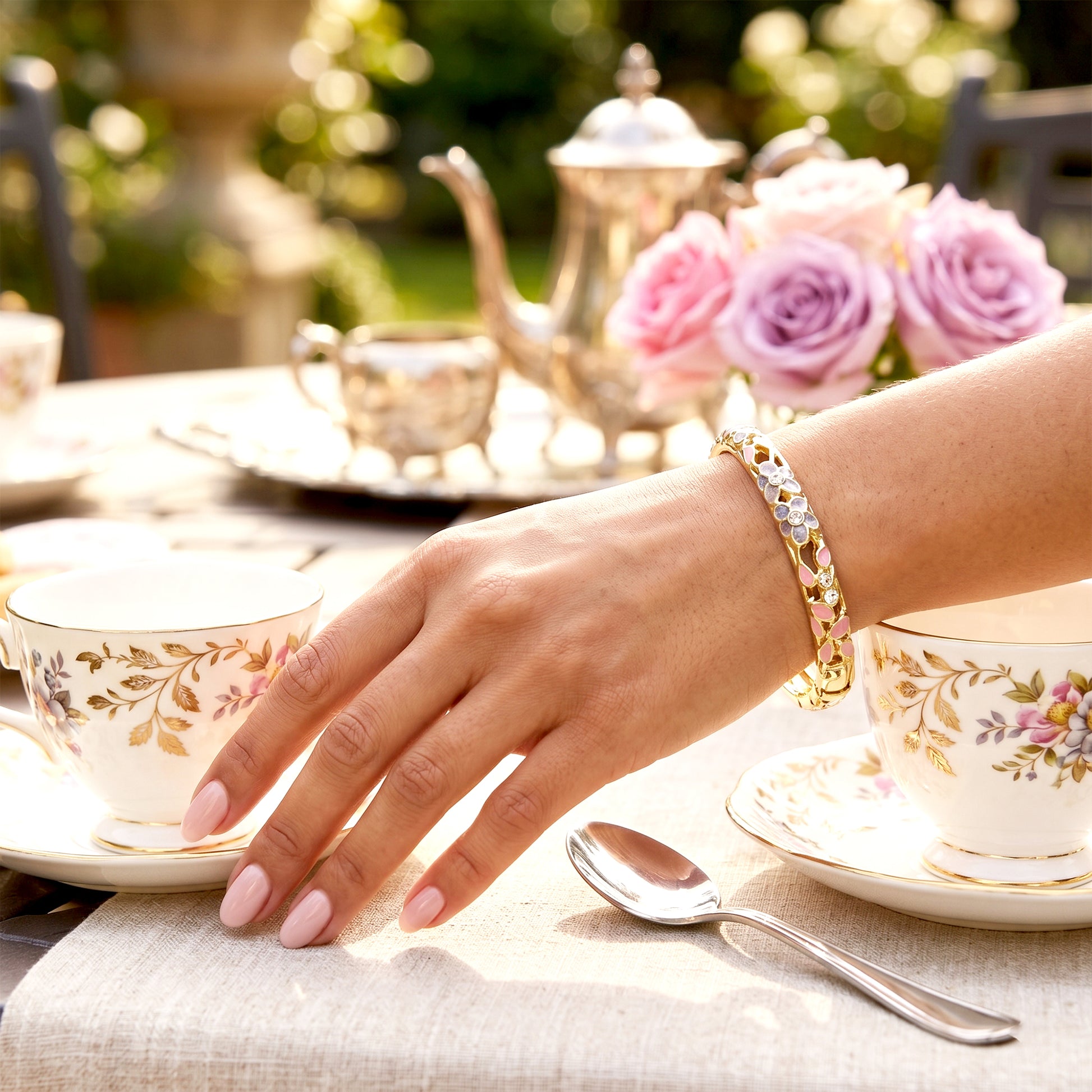 Woman wearing pink floral gold bracelet at tea table