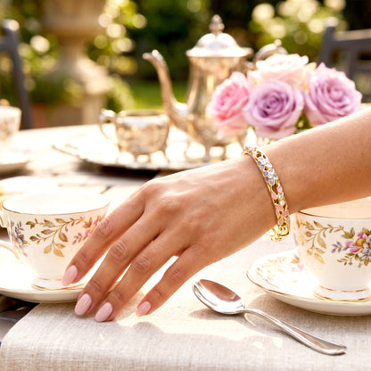 Woman wearing pink floral gold bracelet at tea table