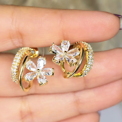 Close-up of gold floral hoop earrings with crystal detailing
