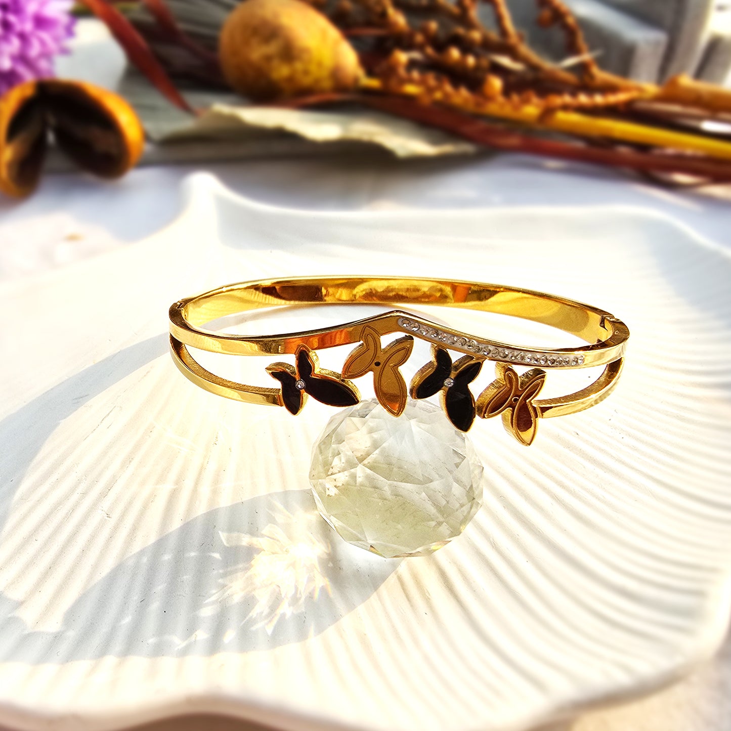 Gold V-shaped bangle with crystal pave line and alternating black and gold butterfly charms.