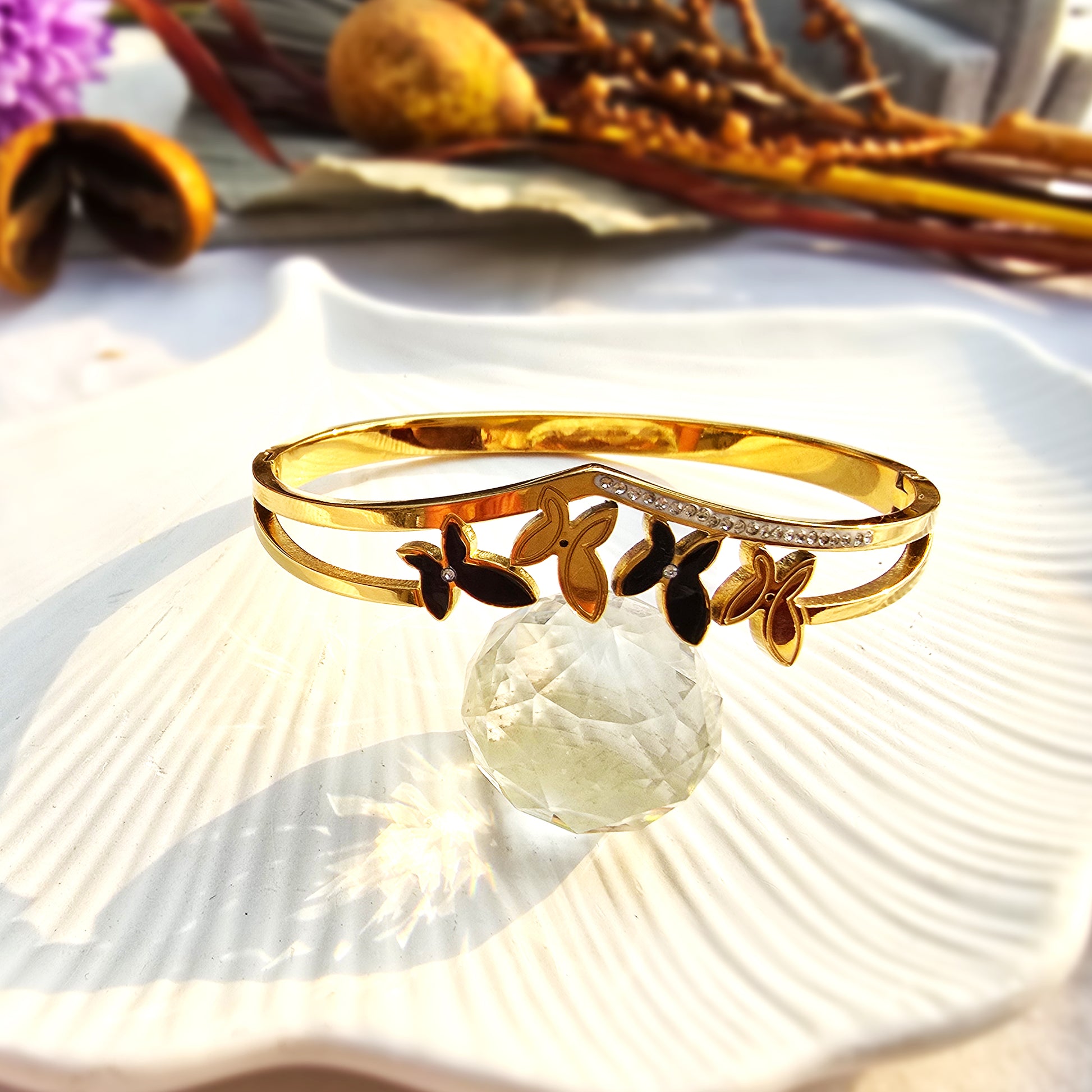 Gold V-shaped bangle with crystal pave line and alternating black and gold butterfly charms.