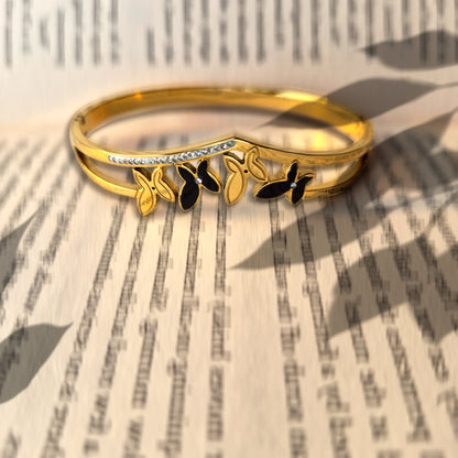 Artistic shot of gold butterfly V-cuff bracelet casting shadows on a book.