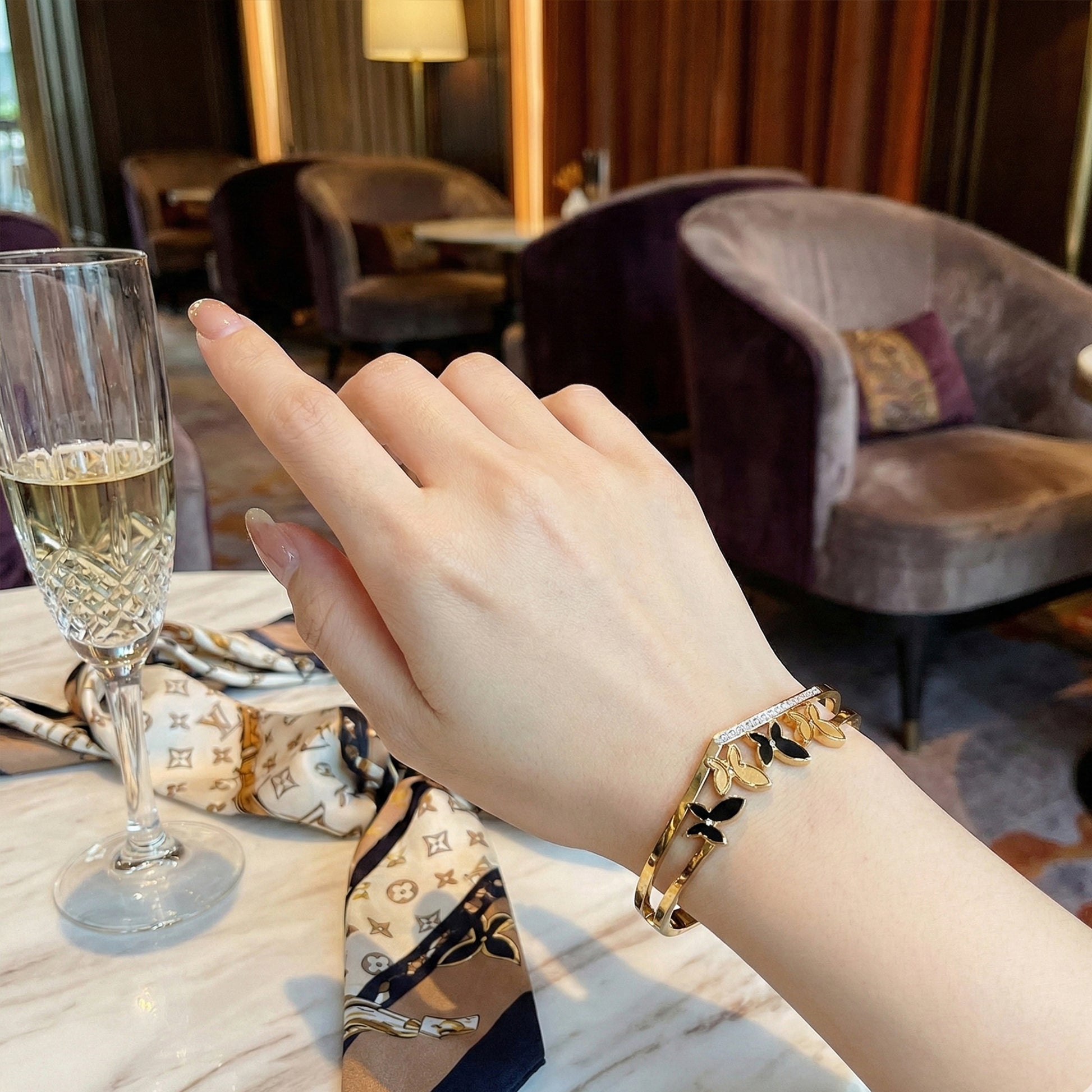 Woman wearing gold V-shaped butterfly bangle styled with crystal accents.