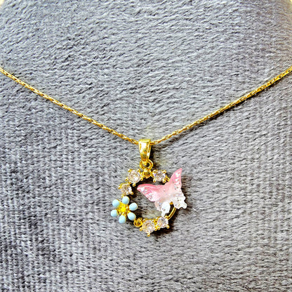 Close-up of crystal and enamel butterfly and flower pendant necklace on a grey textured display.