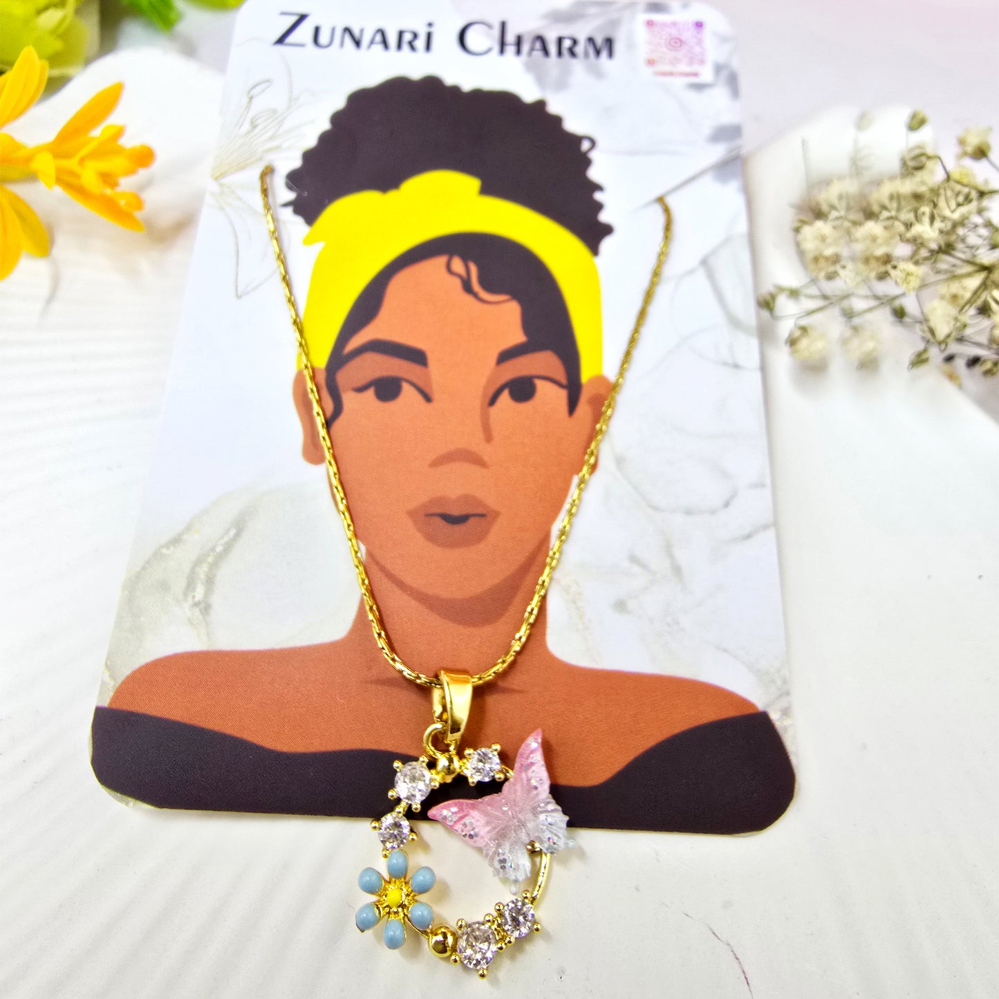 Zunari Charm brand display of the butterfly and flower charm necklace on a jewelry card.