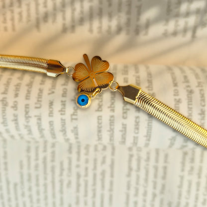 Detailed macro shot of gold four-leaf clover charm on open book pages.