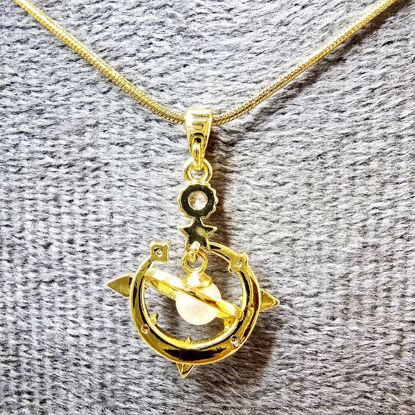 Close-up of Galaxy Charm Pendant showing detailed pearl orb and gold structure with crystals.