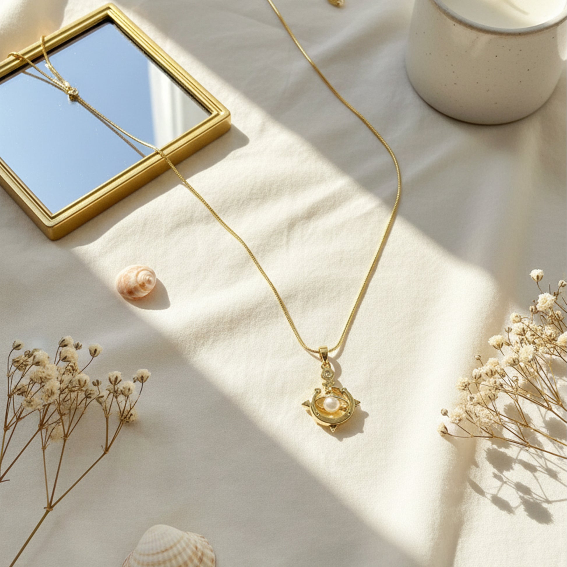 Lifestyle shot of Galaxy Charm Pendant Chain on beige fabric with sunlight and mirror – elegant minimal setup.