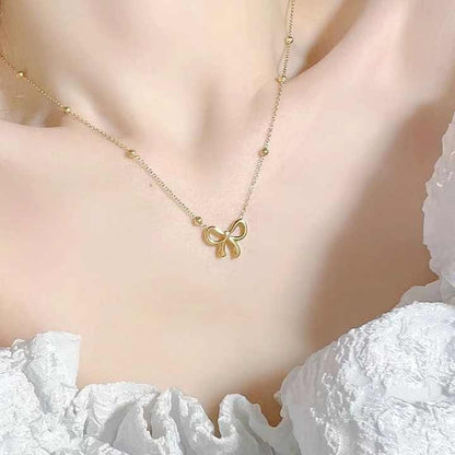 Gold bow pendant necklace worn with a white off-shoulder dress, showcasing its elegant and feminine look.