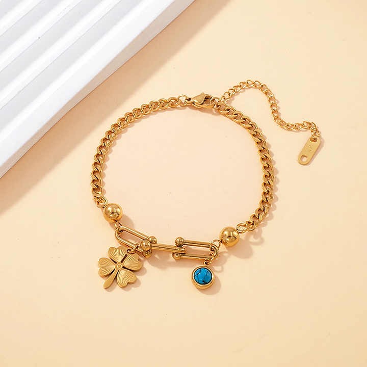 Gold charm bracelet featuring crystal clover and evil eye on adjustable chain